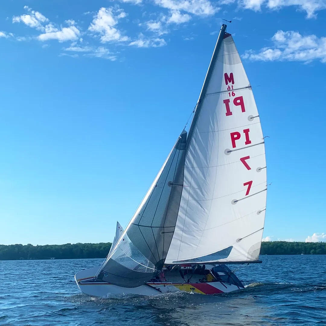 A scow sailboat heeled up as it sails upwind